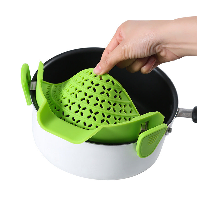 Hand clipping a green silicone strainer onto the rim of a white pot