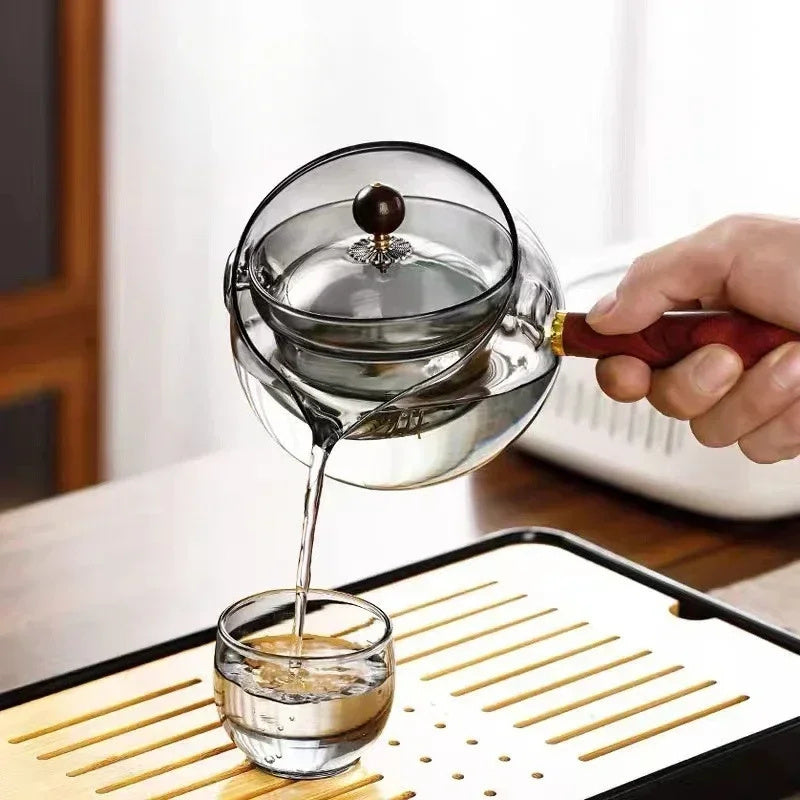 Grey glass teapot with wooden handle on a table edge