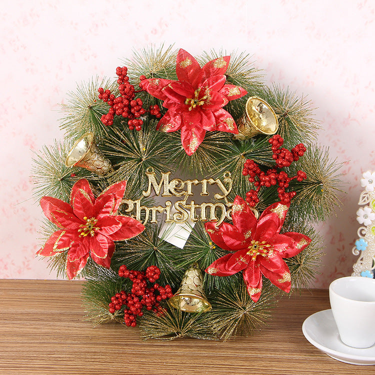 Christmas wreath with three red glitter poinsettias, berries and gold bells on a wooden shelf
