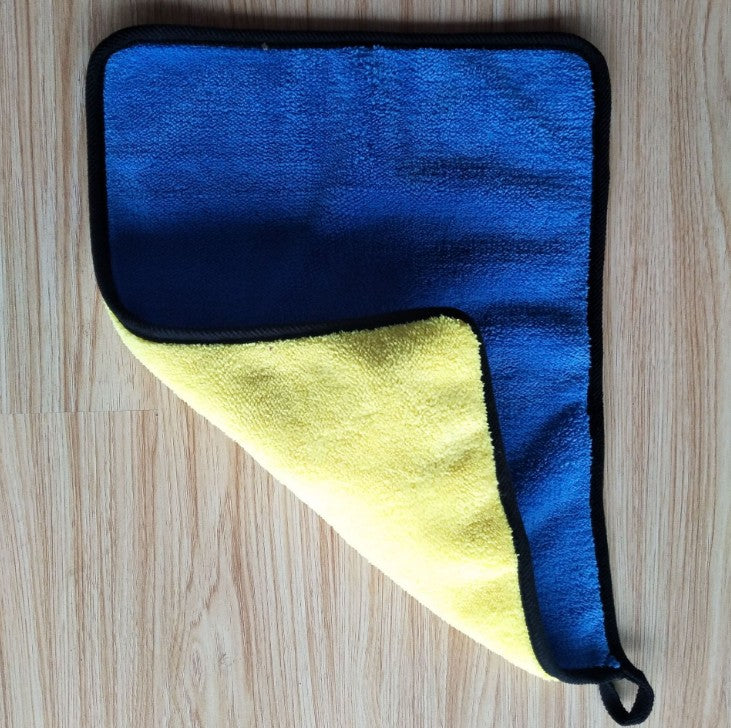 Hand pressing a yellow and grey double-sided cleaning towel