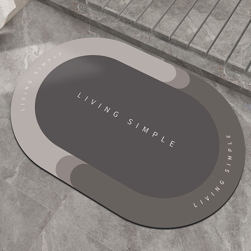 Two-tone light and dark grey oval bath mat on a stone floor