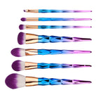 Gold-handled makeup brushes laid out in a row with pink bristles
