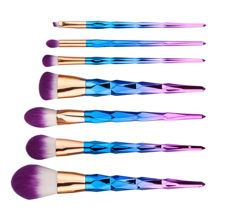 Gold-handled makeup brushes laid out in a row with pink bristles