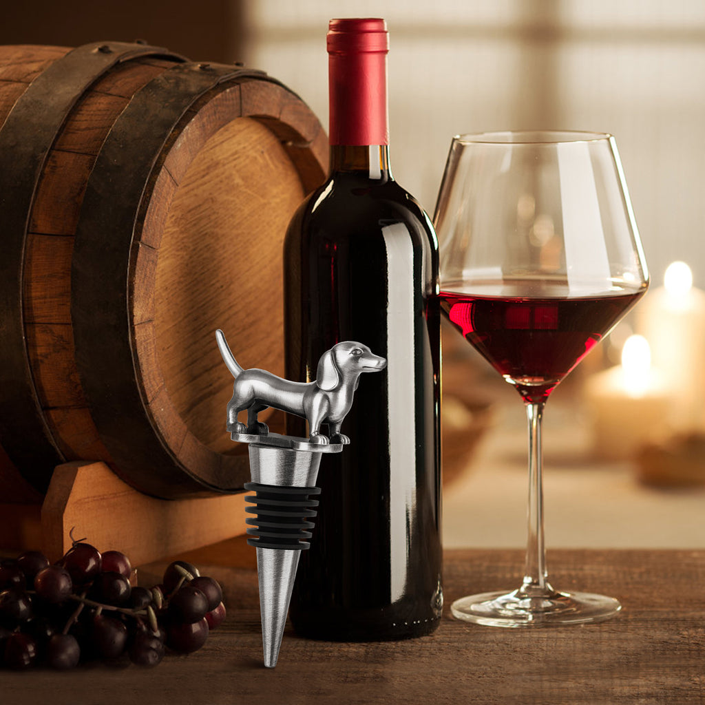 Dark Silver dachshund wine stopper in a bottle beside a glass of red wine