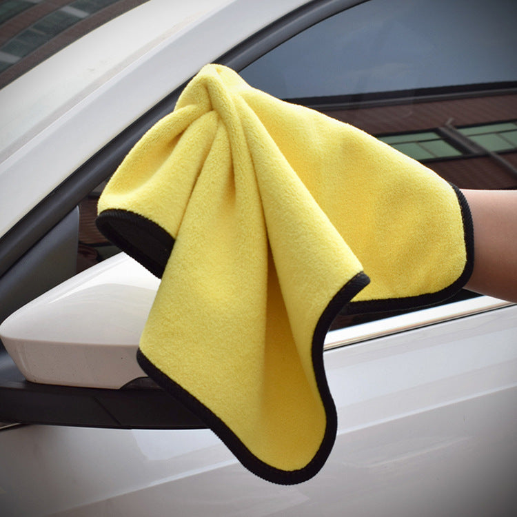 Yellow towel with black edging wiping a white car side mirror