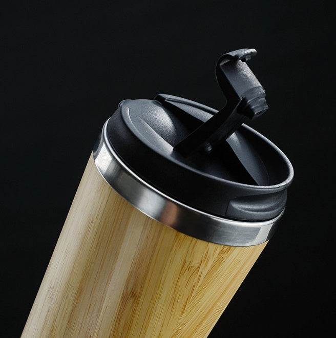 Close-up of a bamboo coffee cup with the black flip-open lid raised