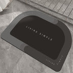 Charcoal grey oval bath mat with a black centre on a stone floor