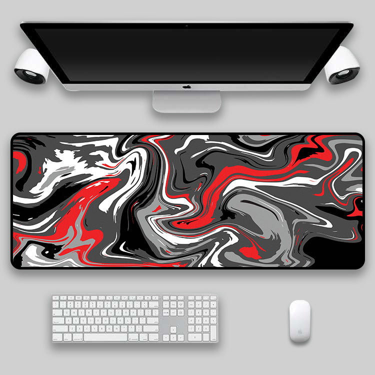 Red, yellow and black swirl desk mat under a laptop with headphones