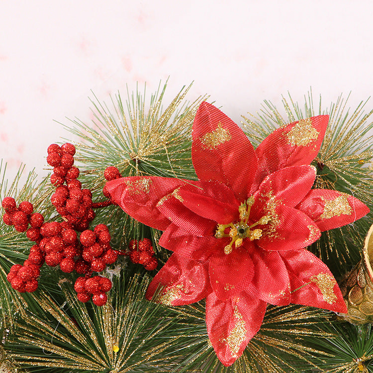 Close-up of a red glitter poinsettia and red berries on pine-needle style greenery
