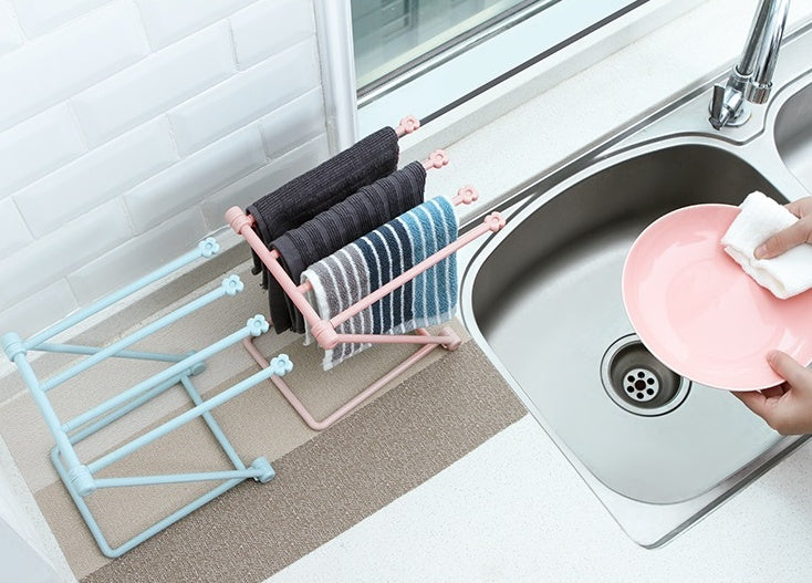 Folding rack at a kitchen sink holding folded dish cloths