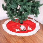 Red and white Christmas tree skirt laid around the base of an artificial tree on a wood floor