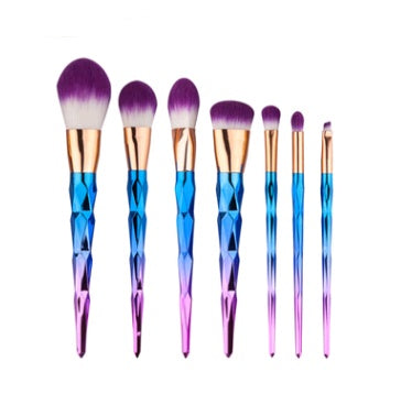 Seven makeup brushes with purple bristles and blue-to-pink diamond-cut handles