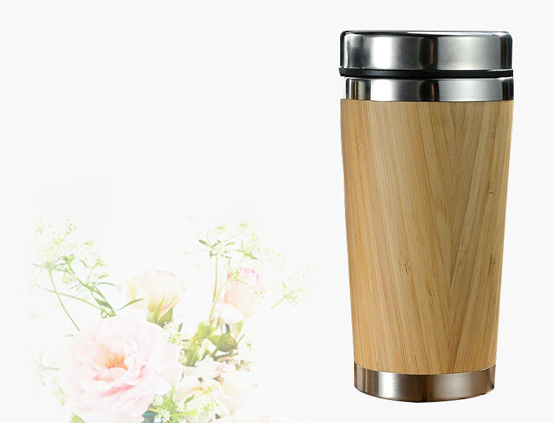 Bamboo coffee cup with a stainless steel cap beside soft pink flowers