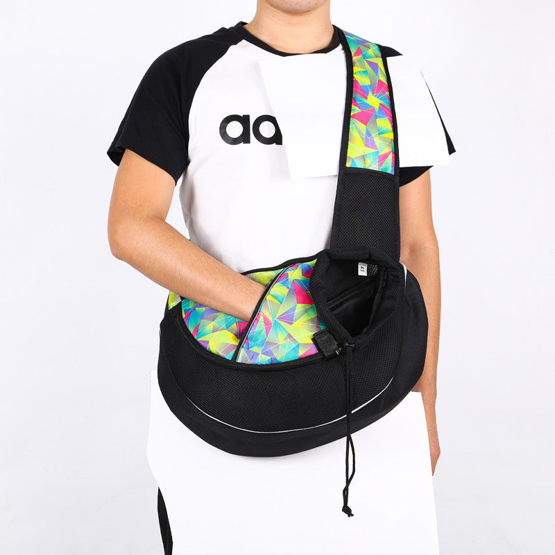 Person wearing a black pet sling carrier with a colourful patterned shoulder strap