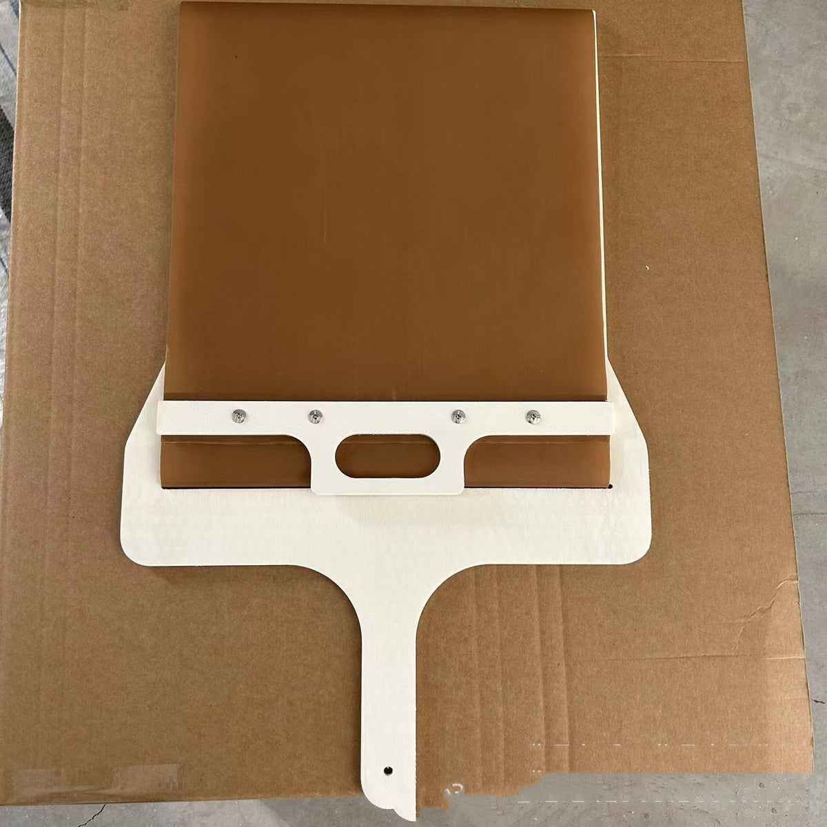 Sliding pizza peel standing upright, showing the handle with hanging hole and belt