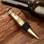Bronze lighthouse wine stopper lying beside a wine bottle on wood
