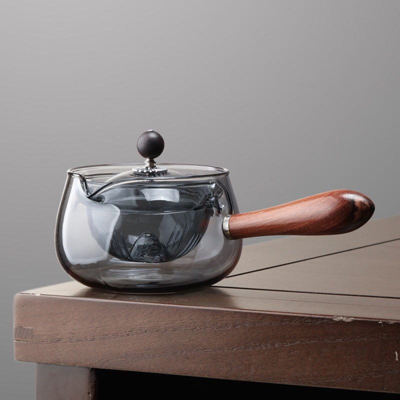 Transparent glass teapot with wooden handle on a wooden table