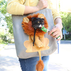 Person carrying a grey lion design pet carrier tote with a cat looking out