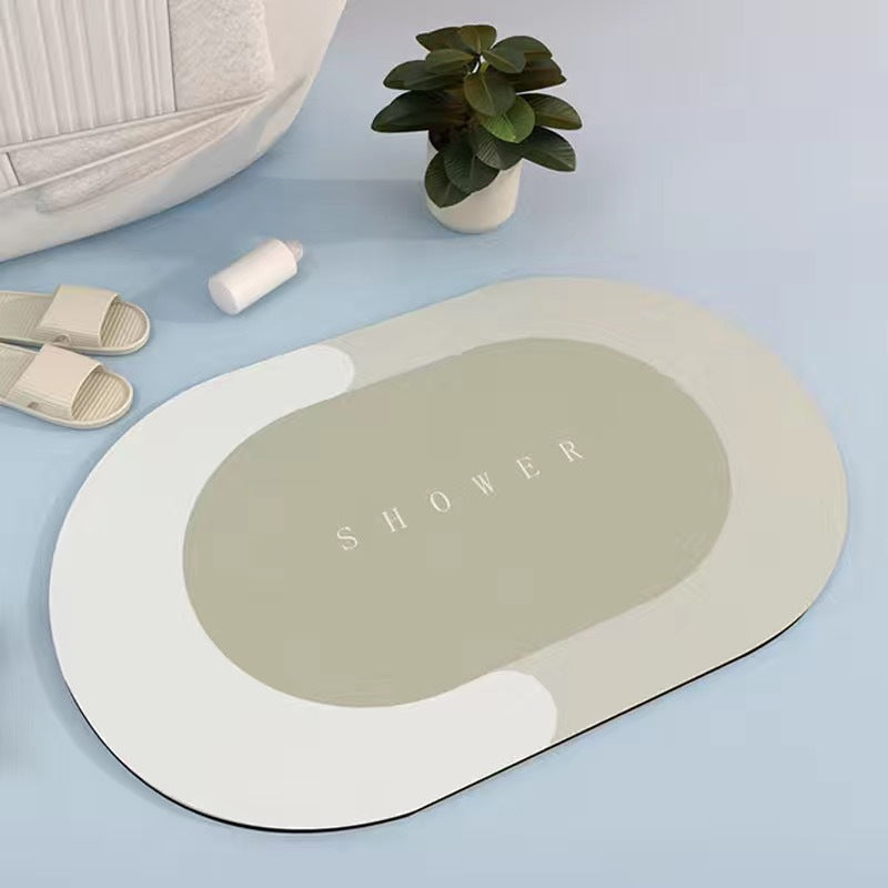 Sage green and cream oval bath mat on a pale blue floor beside slippers and a potted plant