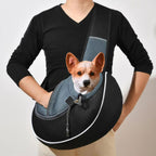 Person wearing a black pet sling carrier with a small brown and white dog looking out