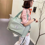 Woman carrying a green foldable duffel bag over her shoulder