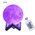 Moon lamp lit in purple on its stand with the remote control, size variant photo