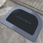 Blue-grey oval bath mat with a black centre on a stone floor