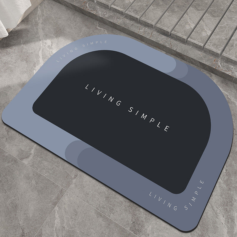 Blue-grey oval bath mat with a black centre on a stone floor
