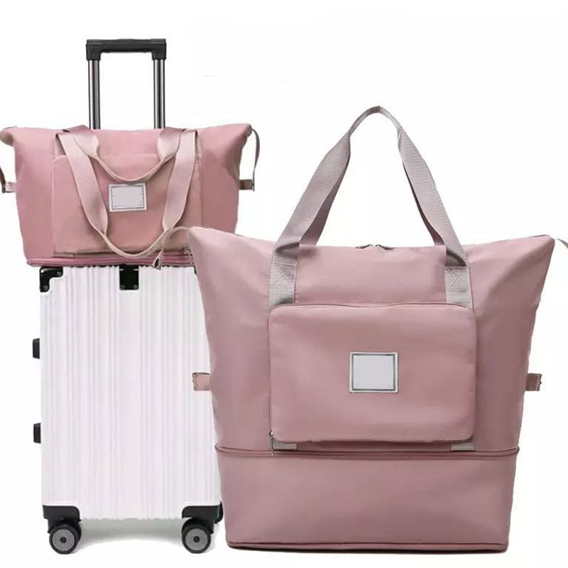 Pink foldable duffel bag beside a rolling suitcase