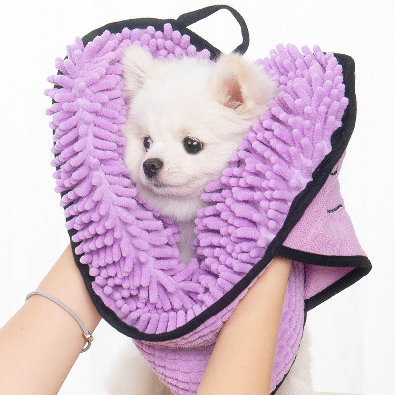 Small dog's head wrapped in a purple chenille pet towel held by hands