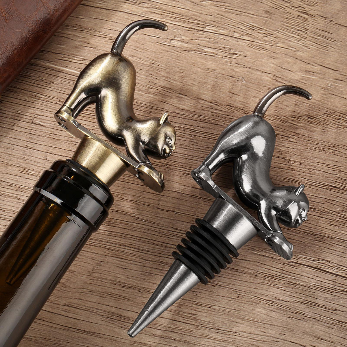 Bronze and Dark Silver stretching cat wine stoppers on a wooden table