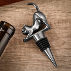 Dark Silver stretching cat wine stopper next to a wine bottle