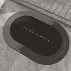 Dark grey-brown oval bath mat with a black centre on a stone floor