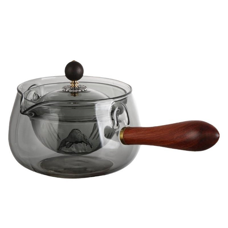 Glass teapot pouring into a small cup on a tea tray