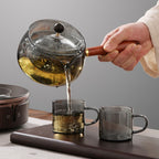 Pouring tea from a glass teapot with wooden handle