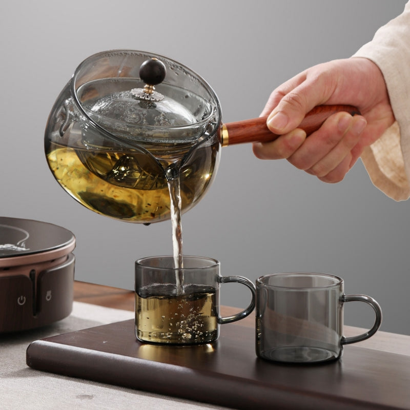 Pouring tea from a glass teapot with wooden handle