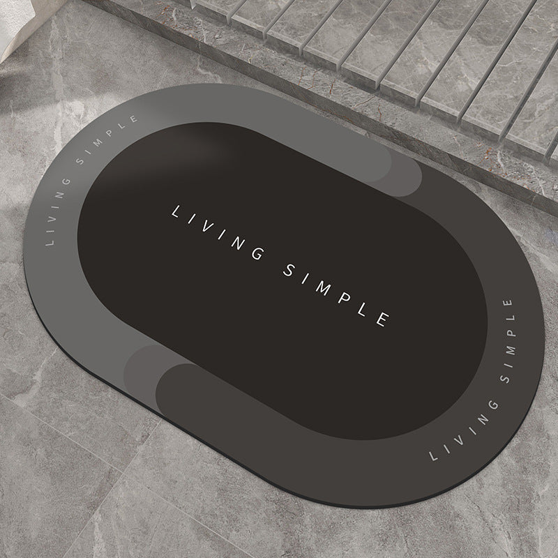 Dark grey oval bath mat with a black centre on a stone floor