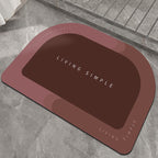 Brick red oval bath mat with a dark brown centre on a stone floor
