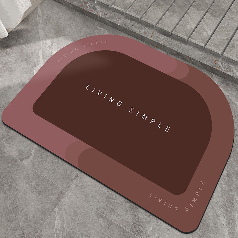 Brick red oval bath mat with a dark brown centre on a stone floor