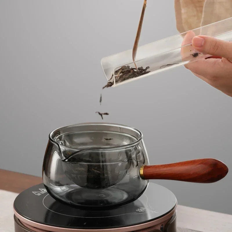 Grey glass teapot with infuser being filled with loose tea