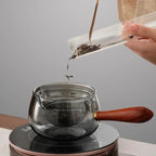 Grey glass teapot with infuser being filled with loose tea