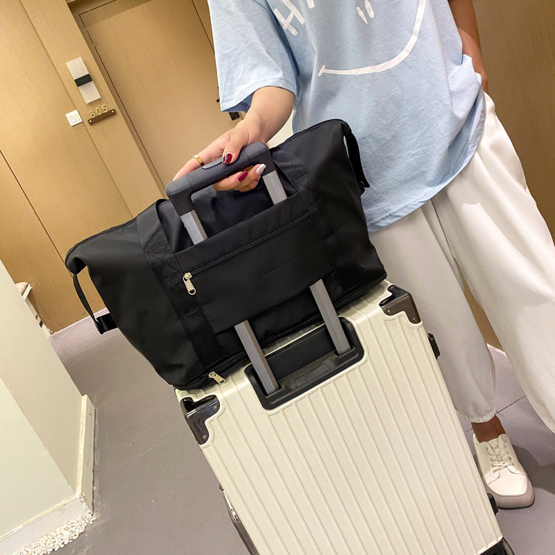 Black foldable duffel bag riding on a suitcase handle with the trolley sleeve