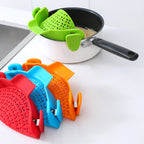 Green strainer clipped to a pan with red, blue and orange strainers in front