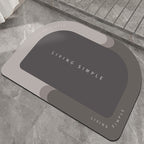 Light grey oval bath mat with a dark grey centre on a stone floor