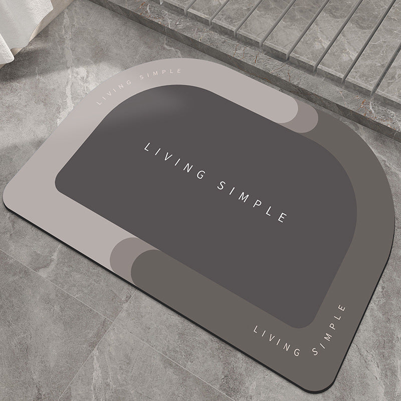 Light grey oval bath mat with a dark grey centre on a stone floor