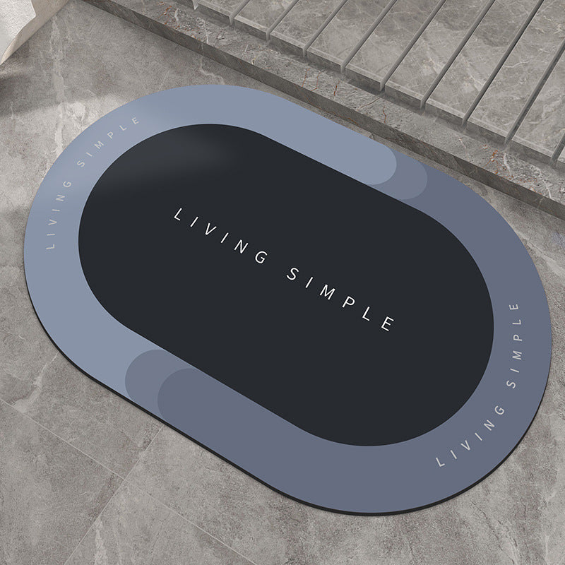 Blue-grey oval bath mat with a navy centre on a stone floor