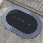 Blue-grey oval bath mat with a navy centre on a stone floor